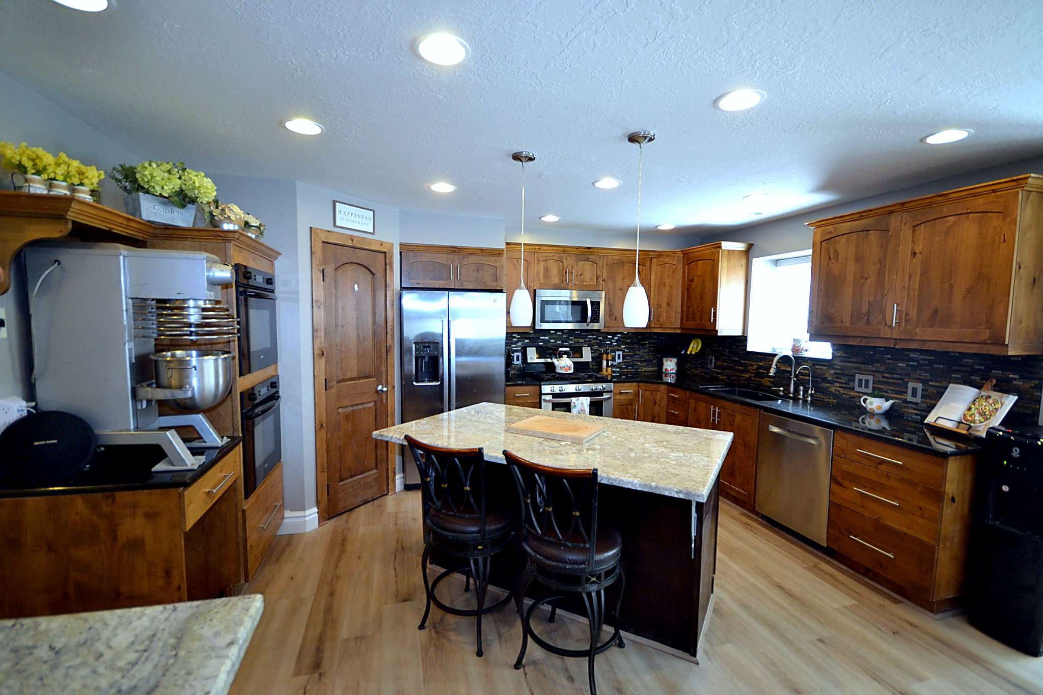 Kitchen featuring a kitchen breakfast bar, decorative light fixtures, stainless steel appliances, a center island, and light wood-style floors