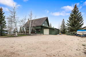 View of property exterior featuring driveway, a chimney, and a shingled roof