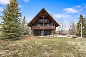 Rear view of house featuring a patio area, a yard, and a chimney