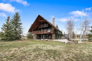 Back of property featuring a lawn, stone siding, and a chimney
