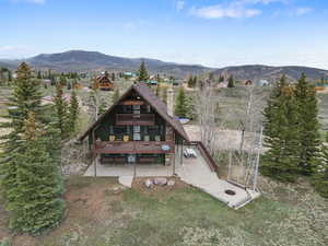 Rear view of property with a mountain view, a chimney, and a balcony