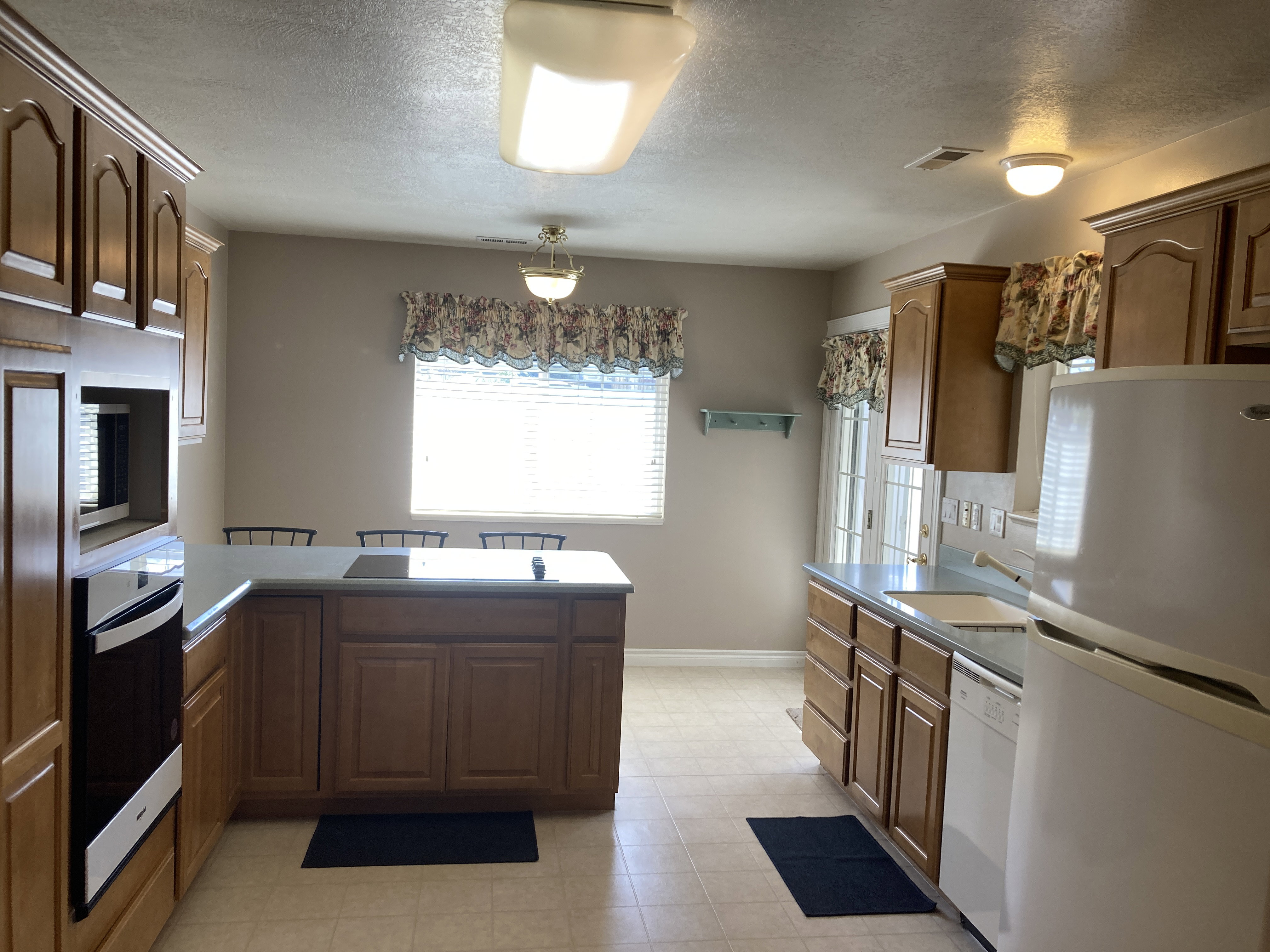 Kitchen featuring stainless steel appliances, a peninsula, wood finish cabinets, and a textured ceiling