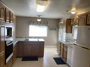Kitchen featuring stainless steel appliances, a peninsula, wood finish cabinets, and a textured ceiling