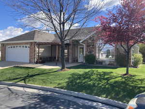 Ranch-style house with brick siding, an attached garage, a front yard, and a shingled roof