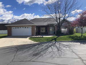 Single story home with brick siding, an attached garage, a shingled roof, concrete driveway, and a patio area