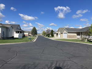View of asphalt road featuring a residential view and curbs