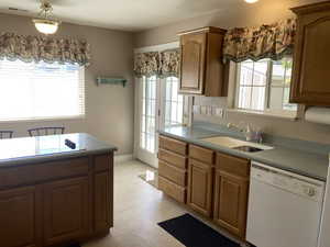 Kitchen featuring white dishwasher, wood finish cabinetry, light tile patterned floors, and black electric cooktop