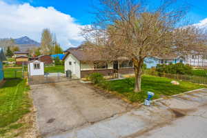View of front of house featuring a gate, asphalt driveway, brick siding, and a shed