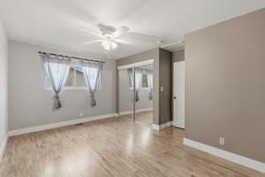 Unfurnished bedroom featuring light wood-type flooring, a closet, and a ceiling fan