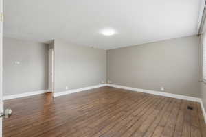 Spare room featuring dark wood-type flooring and baseboards