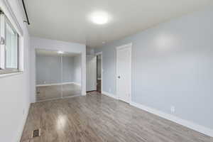 Unfurnished bedroom with wood finished floors and a closet