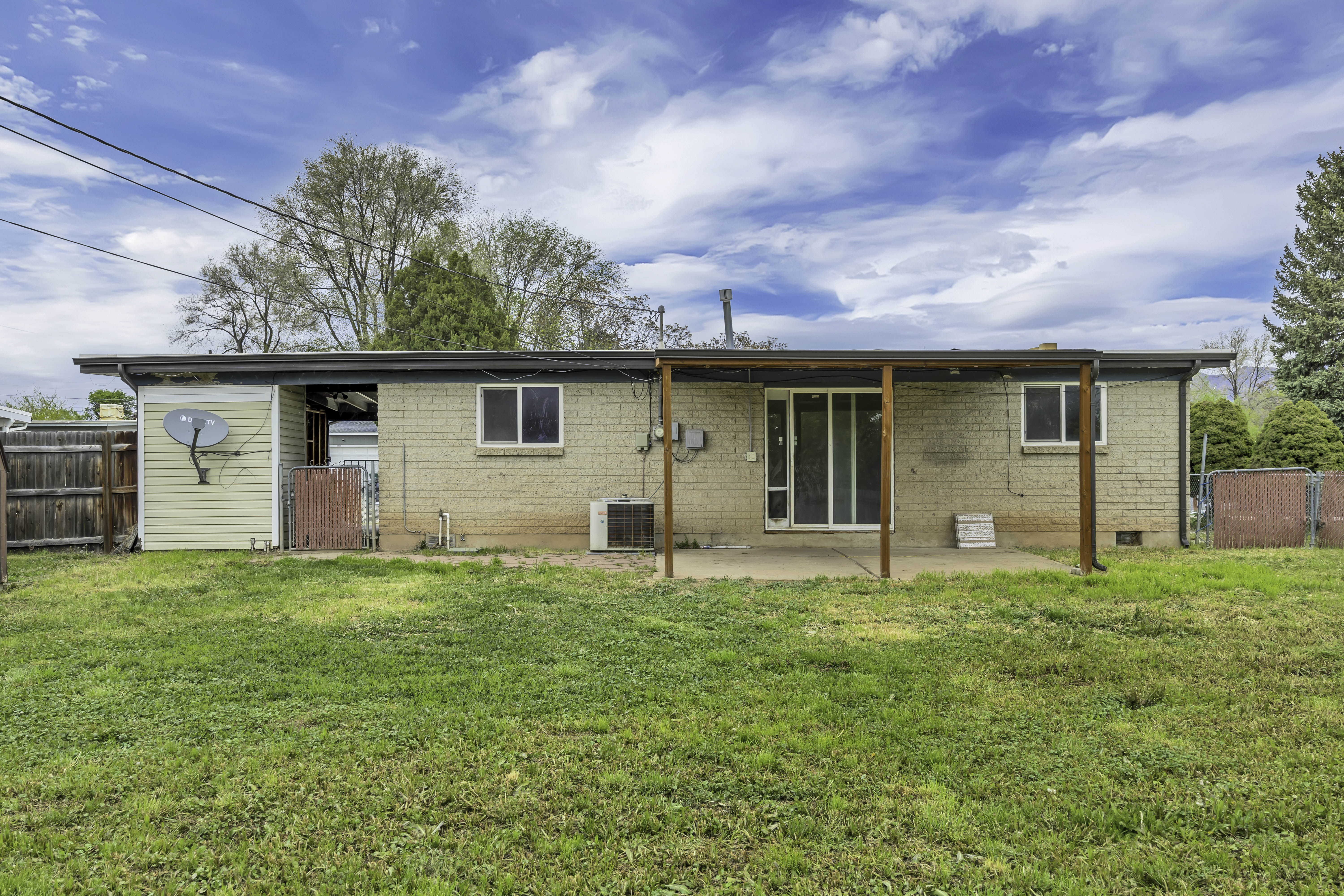 Rear view of property featuring a patio area, brick siding, and a gate