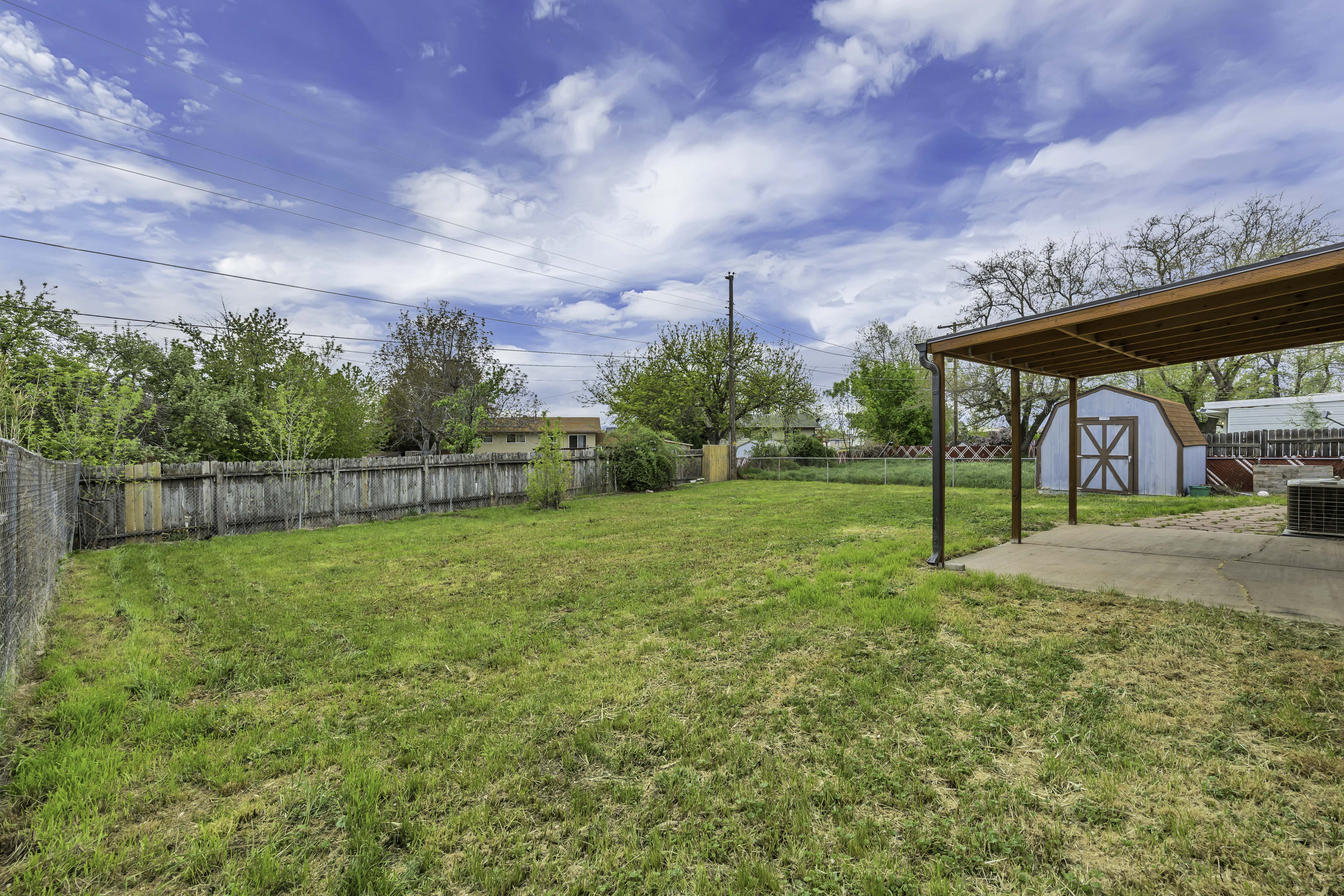 Fenced backyard featuring a storage shed
