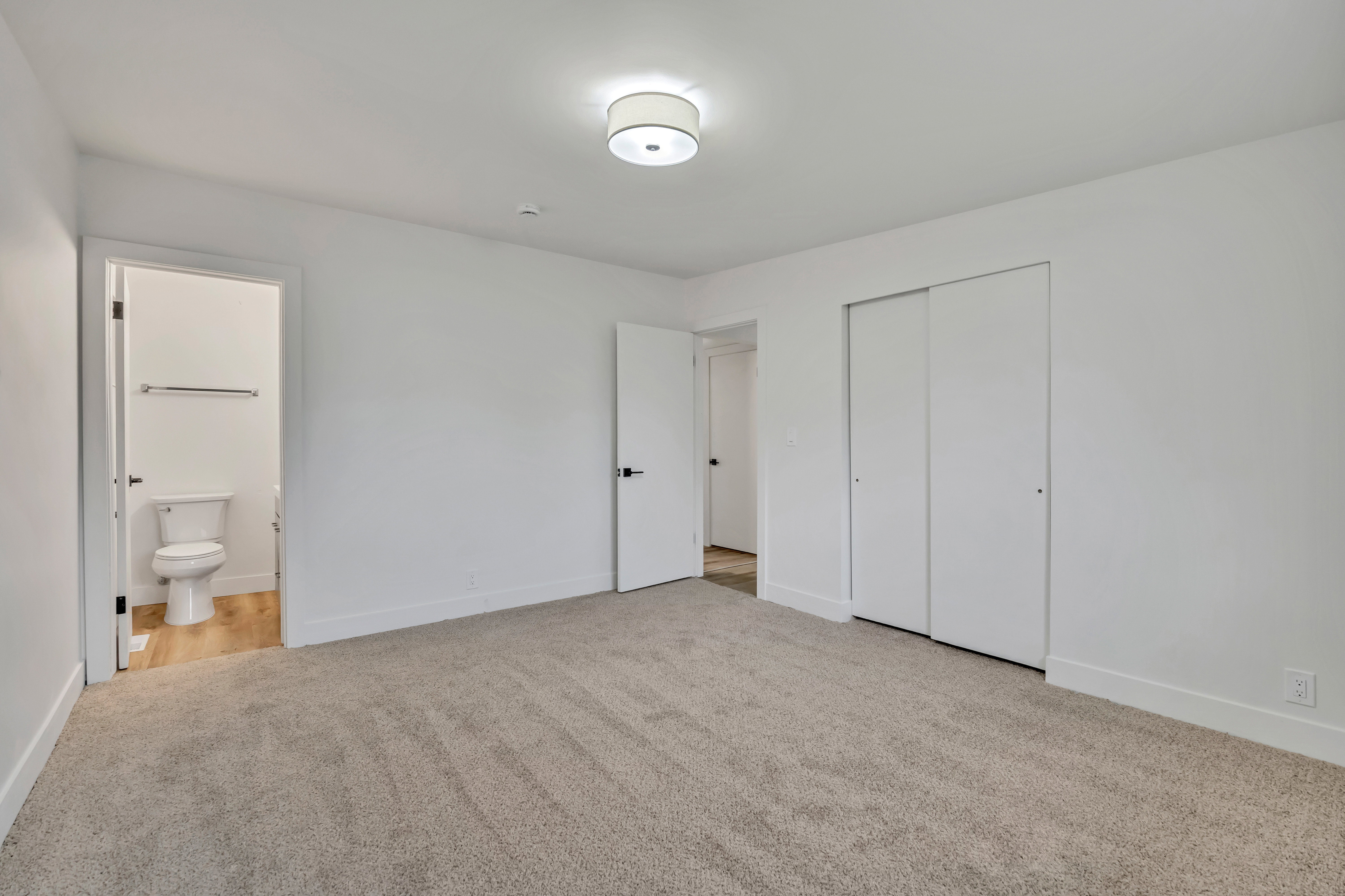 Unfurnished bedroom featuring light colored carpet, a closet, and ensuite bathroom