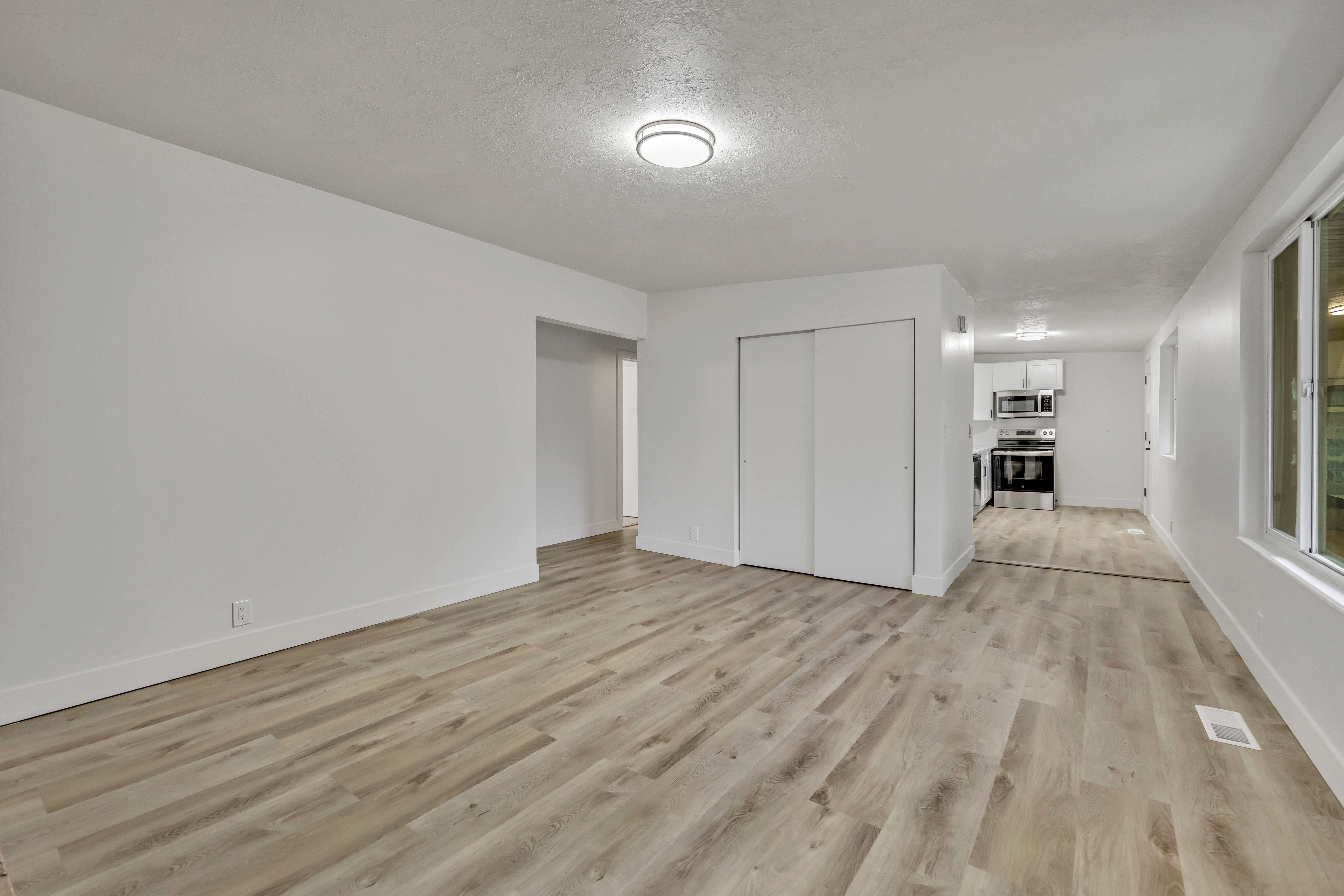 Unfurnished bedroom with light wood-type flooring, a closet, and a textured ceiling