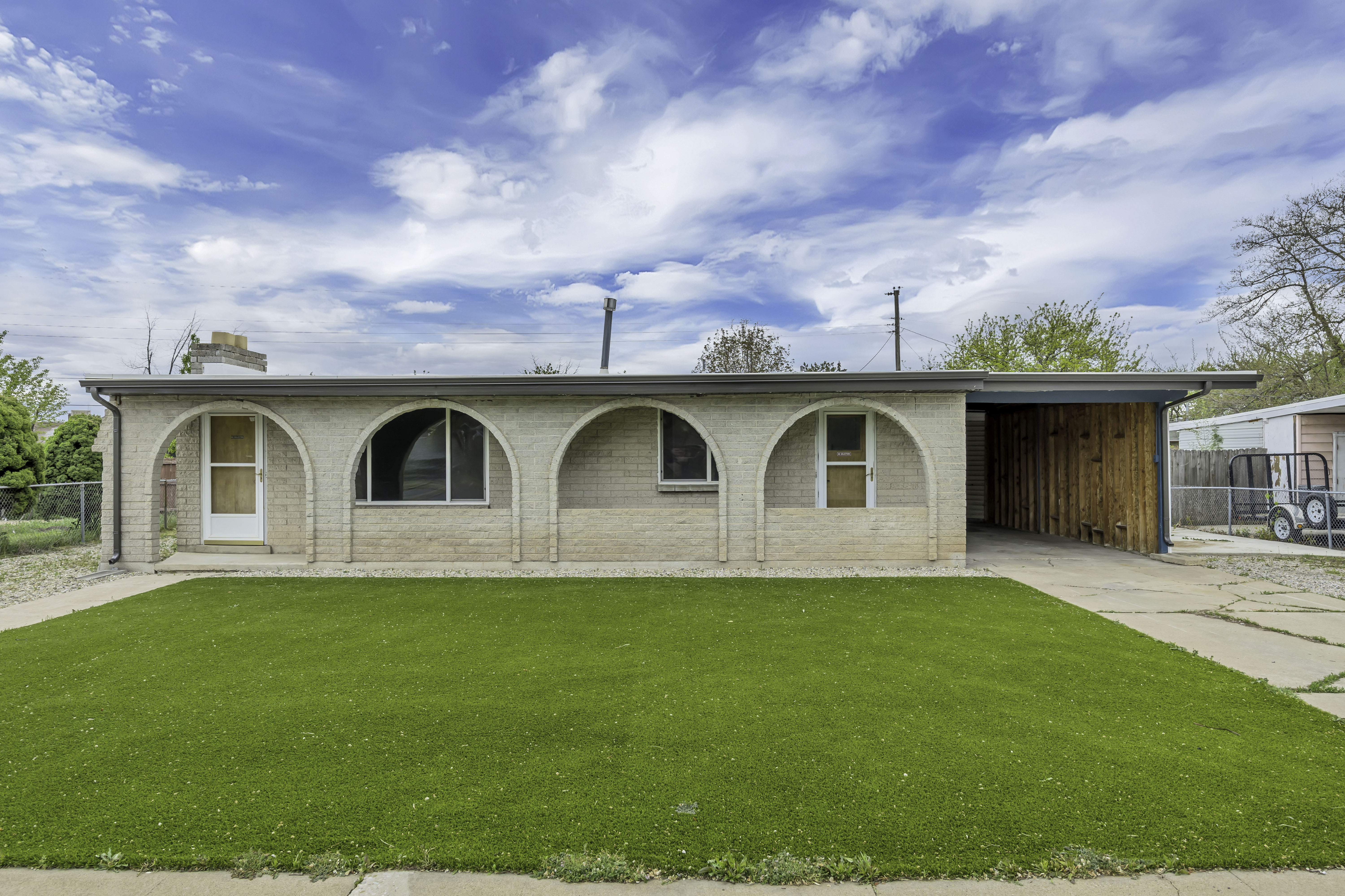 View of front of home with a carport, a chimney, driveway, and brick siding