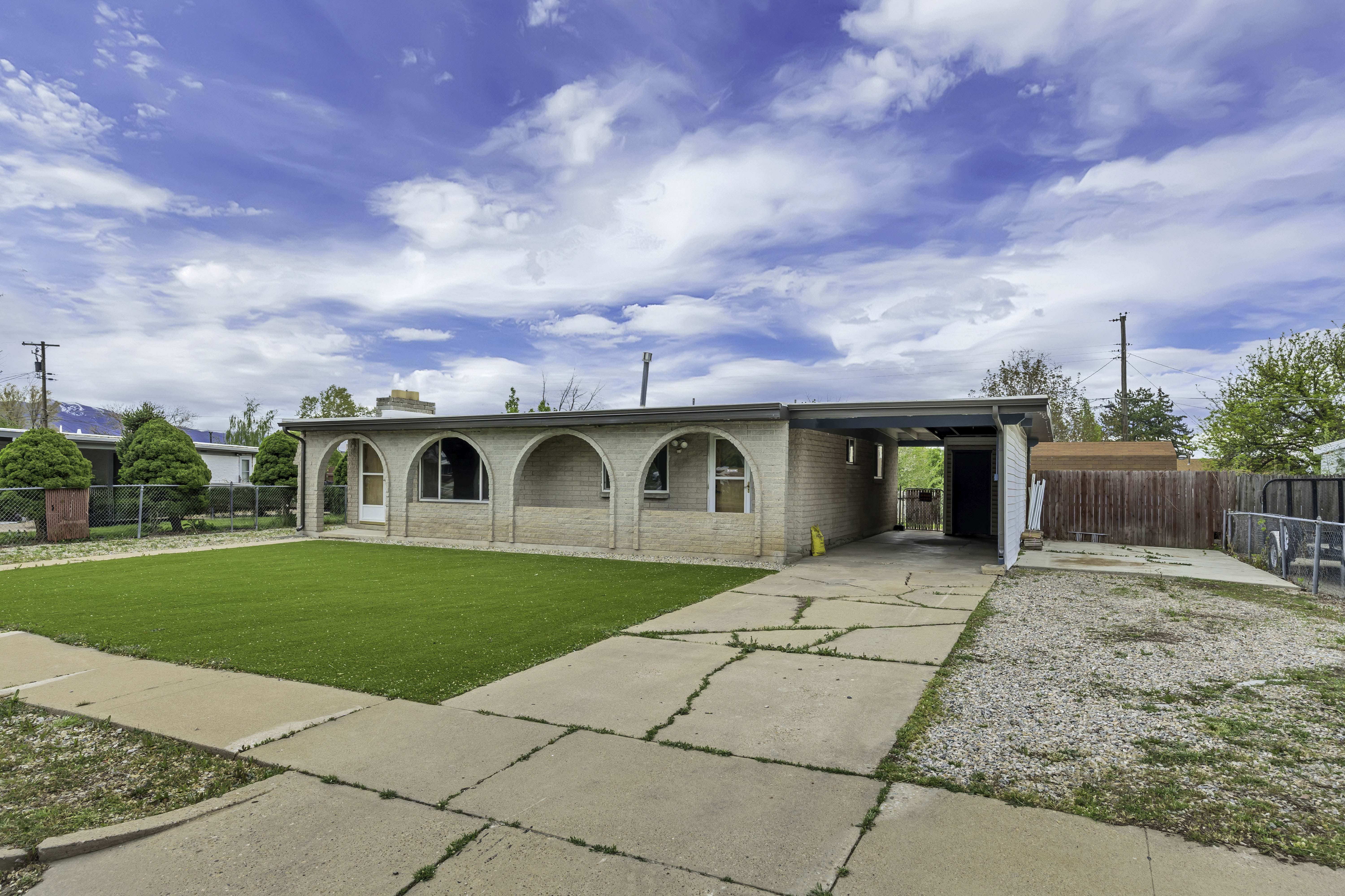View of front facade with an attached carport, concrete driveway, and brick siding