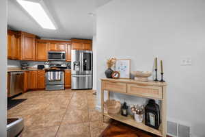 Kitchen with wood finish cabinetry, stainless steel appliances, and light tile patterned floors