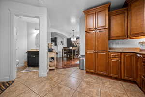 Kitchen featuring arched walkways, light tile patterned floors, light stone counters, and wood finish cabinets