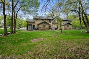 Back of house featuring stucco siding, a yard, and stone siding