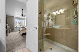 Full bath with light colored carpet, connected bathroom, a shower stall, and ceiling fan