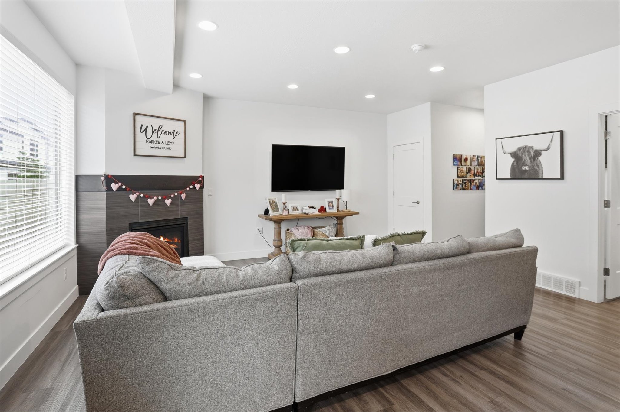 Living room with wood finished floors, a lit fireplace, and recessed lighting