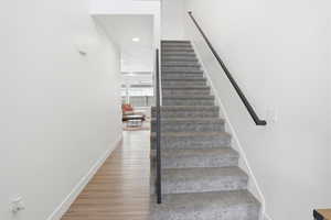 Stairway with wood finished floors and recessed lighting