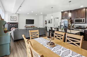 Dining space with dark wood-style floors, recessed lighting, and a fireplace