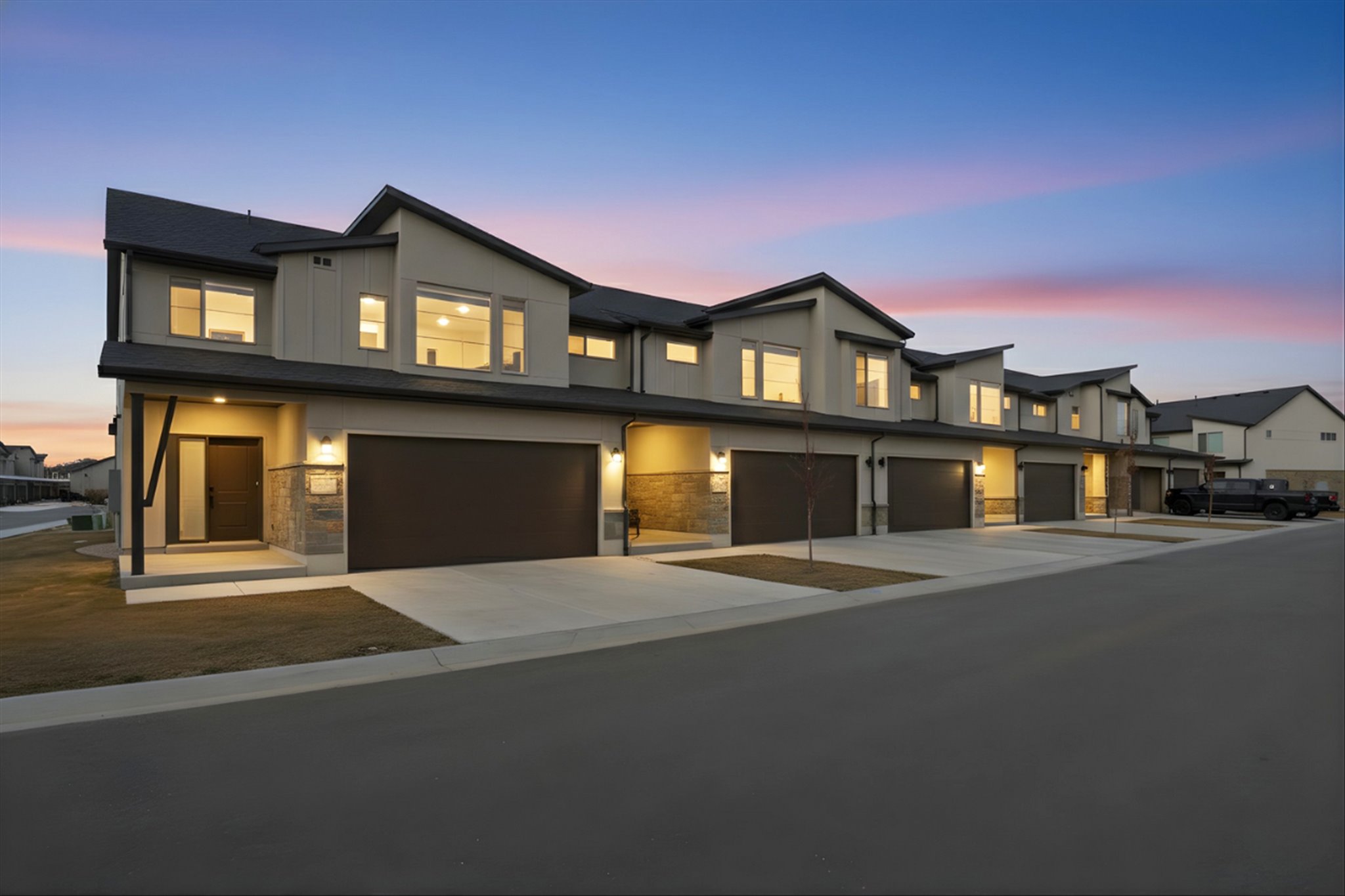 Contemporary house featuring driveway, an attached garage, stone siding, and stucco siding