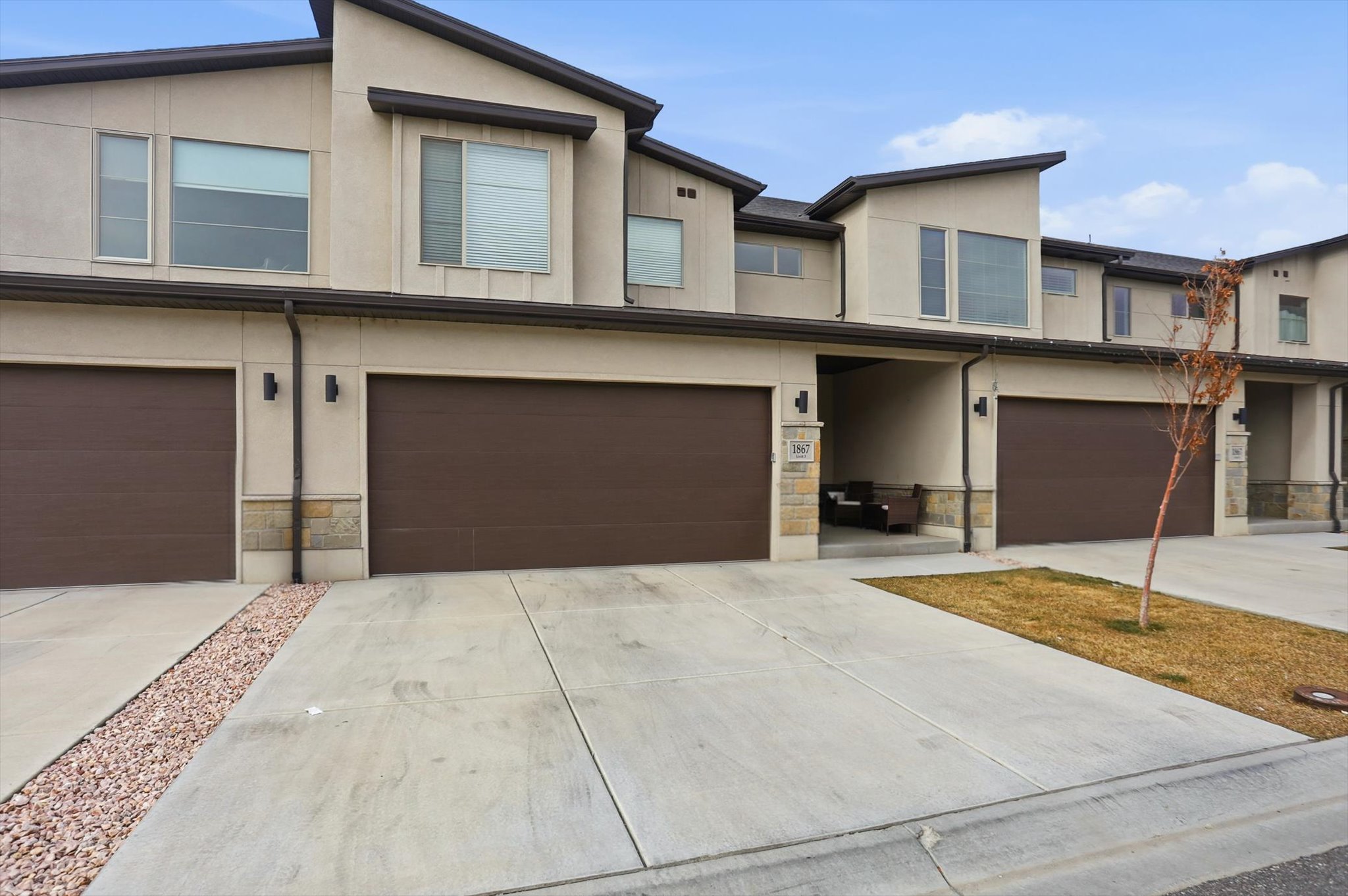 Contemporary house featuring stone siding, stucco siding, and an attached garage