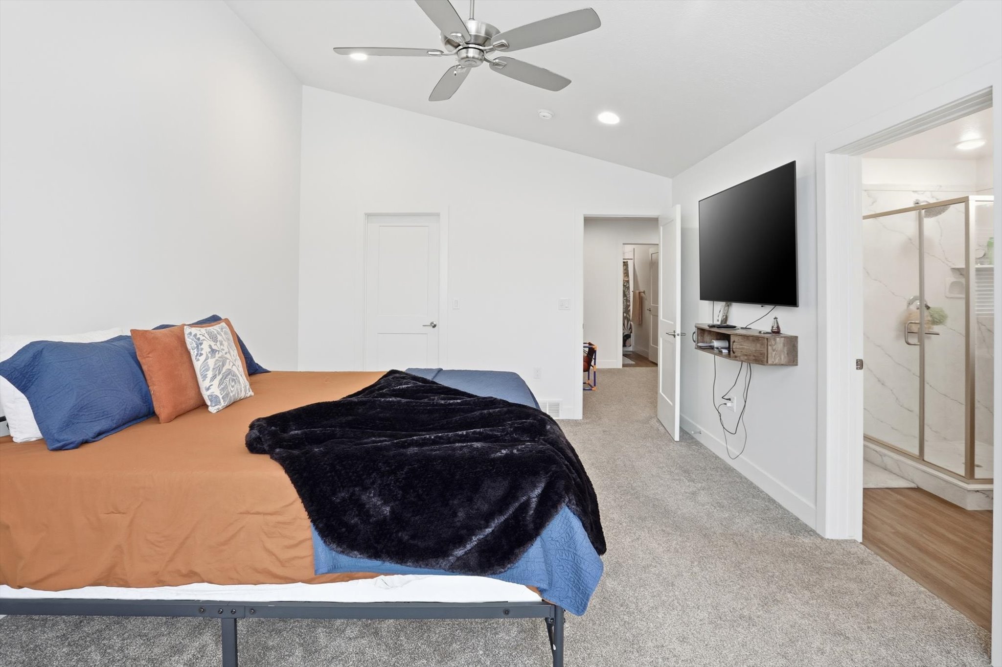Bedroom featuring light colored carpet, vaulted ceiling, a ceiling fan, recessed lighting, and ensuite bath