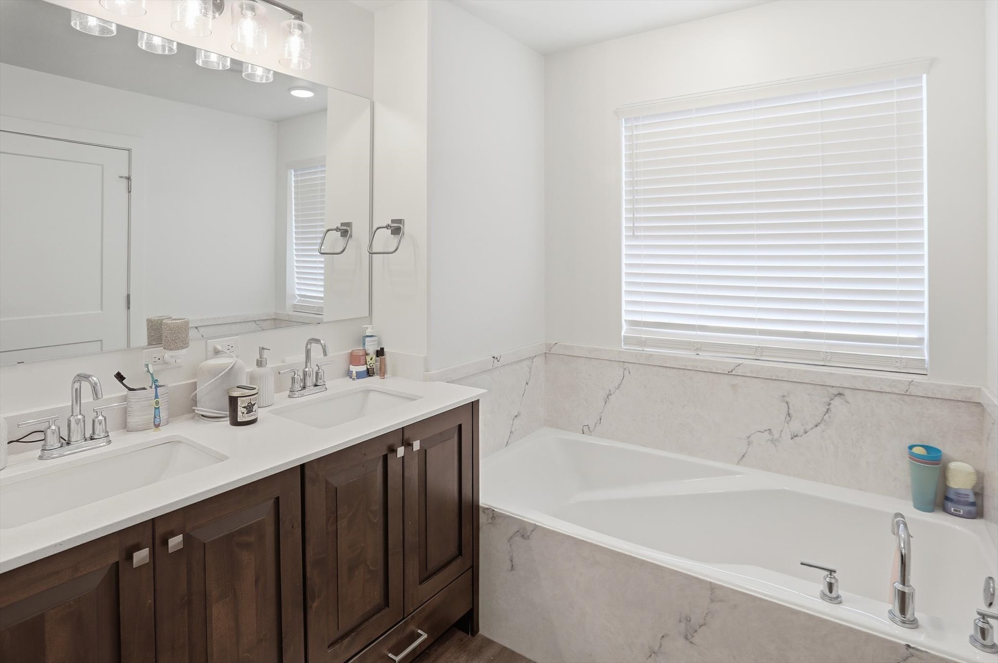 Full bath with double vanity, a bath, and plenty of natural light
