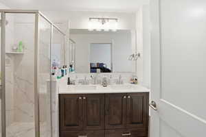 Ensuite bathroom featuring double vanity and a marble finish shower
