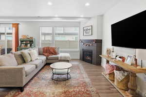 Living room with a glass covered fireplace, recessed lighting, and wood finished floors