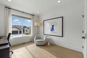 Office with light wood-type flooring and recessed lighting