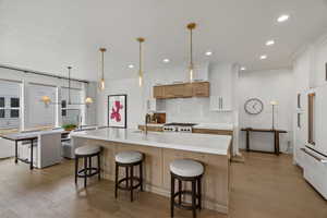 Two tone kitchen featuring two tone color scheme, light wood-style flooring, decorative light fixtures, a kitchen bar, and high end white refrigerator