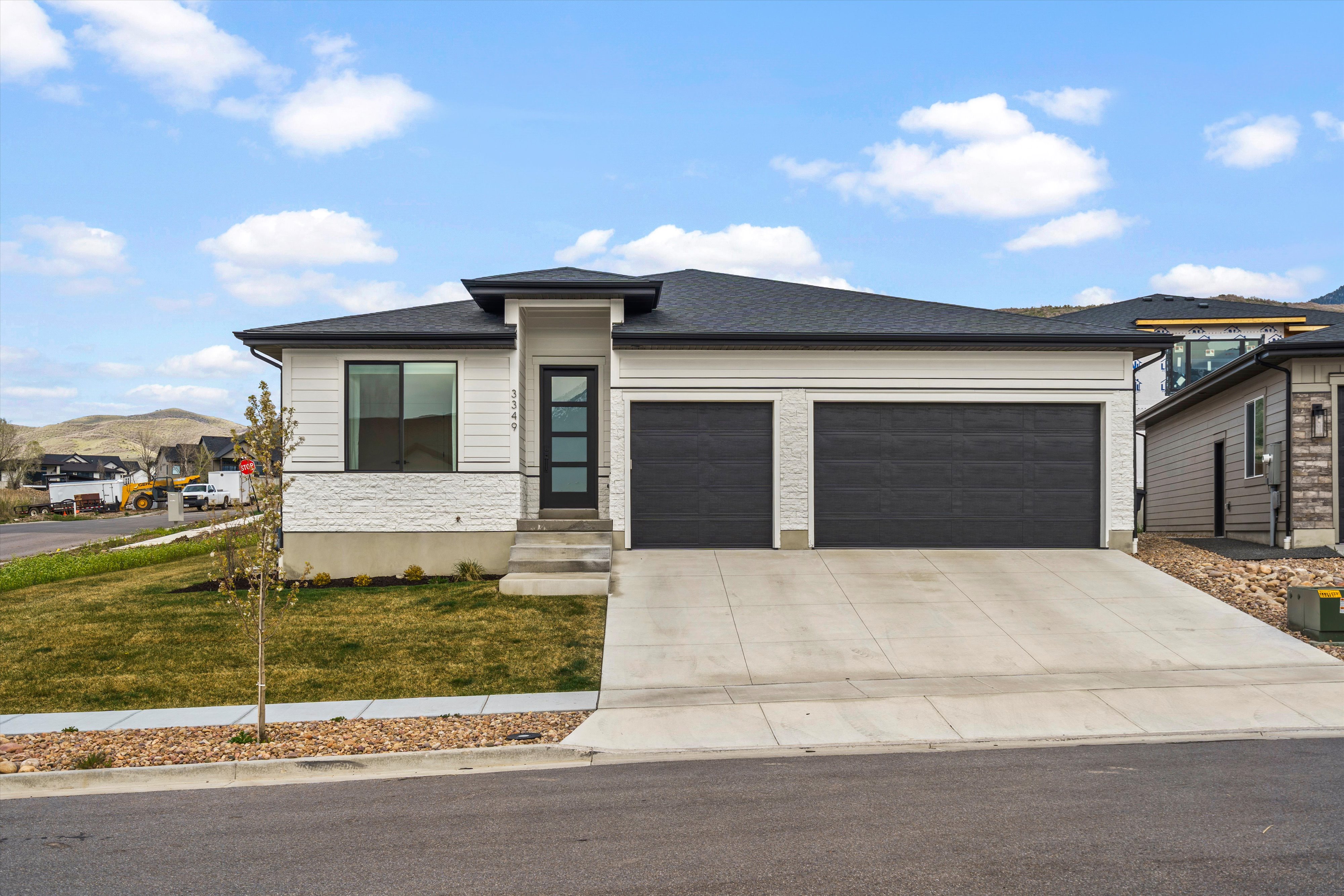 Prairie-style house featuring a garage, concrete driveway, a front yard, a mountain view, and roof with shingles