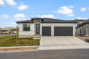 Prairie-style house featuring a garage, concrete driveway, a front yard, a mountain view, and roof with shingles