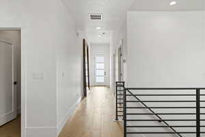 Hallway with light wood-type flooring and recessed lighting