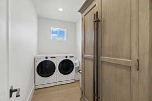 Laundry room featuring light wood finished floors, washing machine and dryer, and recessed lighting