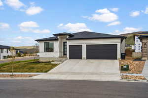 Prairie-style house featuring a mountain view, an attached garage, driveway, a front lawn, and roof with shingles