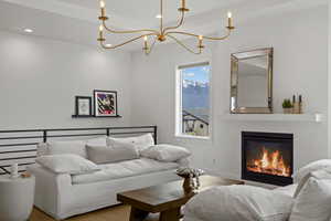 Living area with suspended lighting, wood finished floors, a glass covered fireplace, and a mountain view
