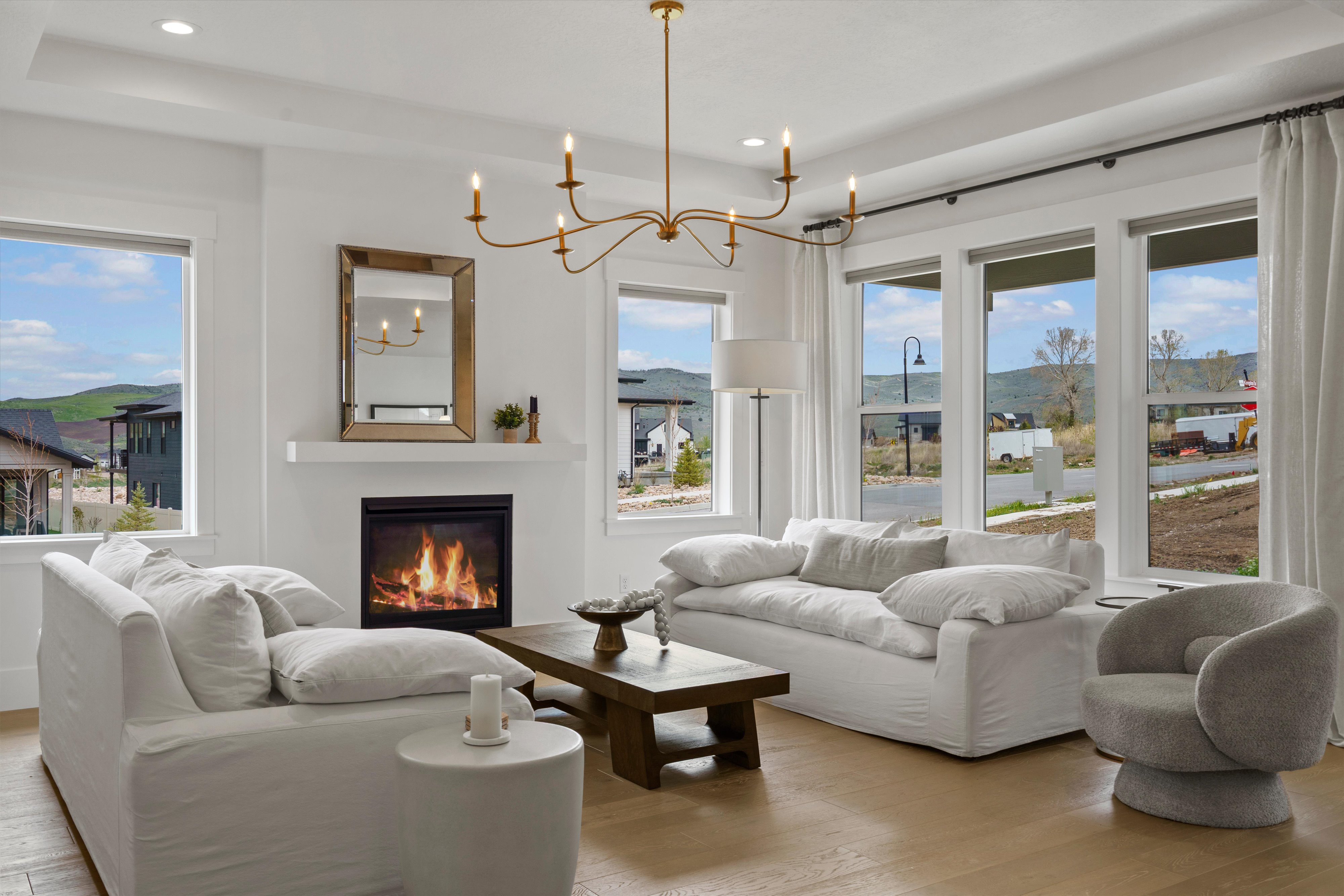 Living room with light wood-style flooring, hanging lights, a glass covered fireplace, and a raised ceiling