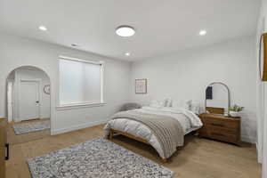 Bedroom featuring arched walkways, light wood-type flooring, and recessed lighting