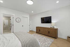 Bedroom with light wood-type flooring, recessed lighting, and ensuite bathroom