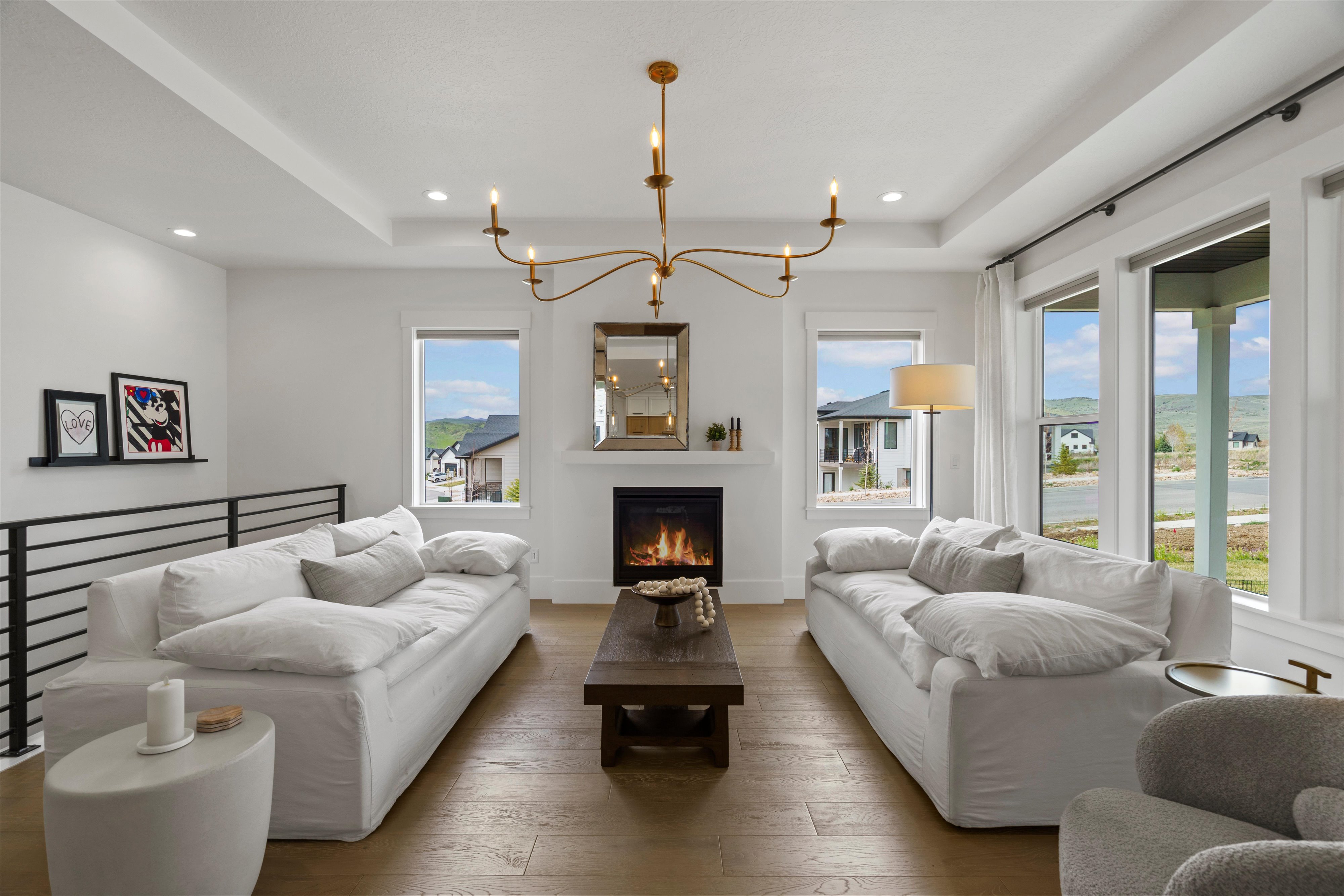 Living area featuring hanging lights, a raised ceiling, hardwood / wood-style flooring, and a lit fireplace