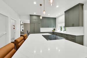 Kitchen featuring a breakfast bar area, light stone counters, healthy amount of natural light, and pendant lighting