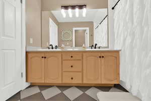 Full bath with curtained shower, double vanity, and light flooring