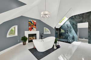Bathroom featuring a soaking tub, a marble finish shower, a lit fireplace, plenty of natural light, and vaulted ceiling