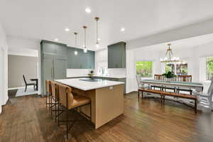 Kitchen with dark wood-style flooring, a chandelier, a kitchen breakfast bar, and a center island